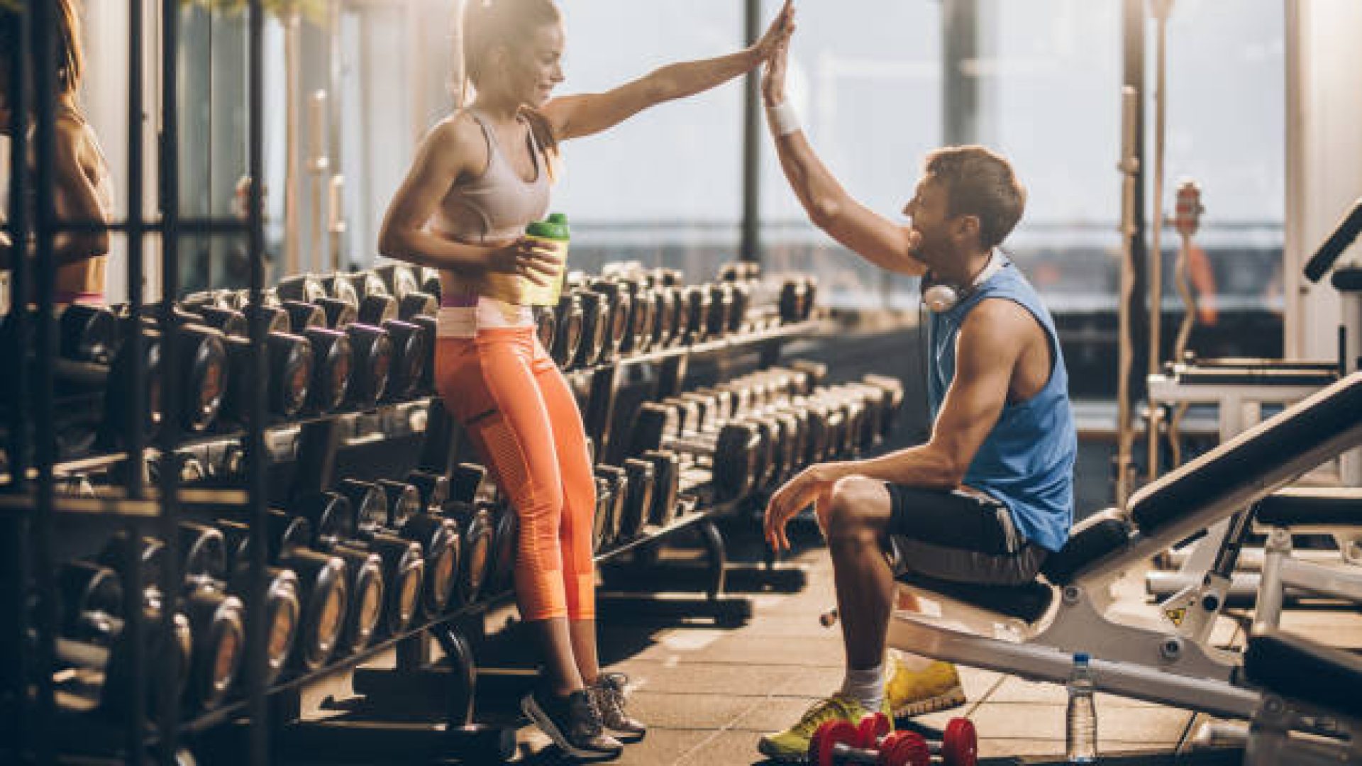 Happy athletic couple giving each other high five after finishing sports training in a gym.